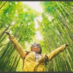 A picture of a happy girl standing in a green forest was set as a featured image for the article How to Support Environmentally Friendly and Sustainable Travel
